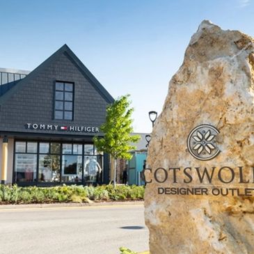 Entrance to Cotswold Designer Outlet with Tommy Hilfiger store visible.
