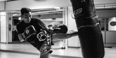 Young boy practicing a high kick on a punching bag in a gym.
