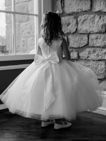 Little girl in fancy dress looking out a window.