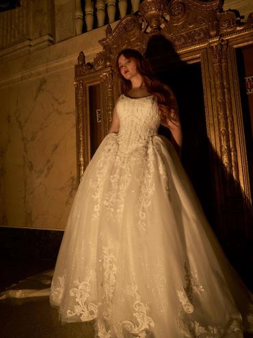 Woman in an elegant white wedding gown standing regal.