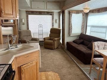 Interior of a cozy RV living space with chairs and a sofa.