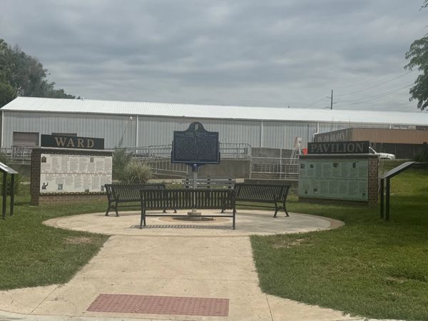 Outdoor seating area with historical plaques and benches under cloudy sky.