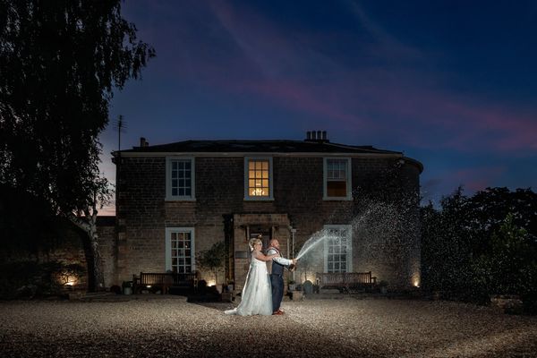 bride and groom spraying champagne in golden hour portraits at Cockliffe Country House, Nottingham