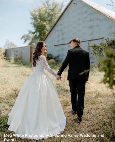 Newlyweds walking in front of an old barn. 