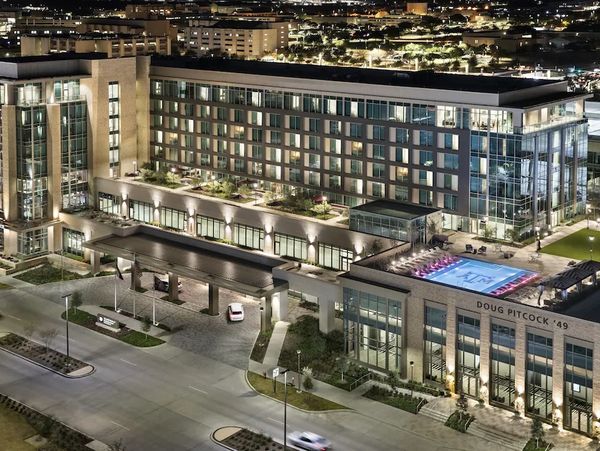 Modern hotel building with a rooftop pool at night.