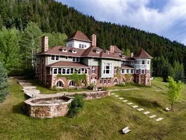 Large countryside mansion surrounded by trees.