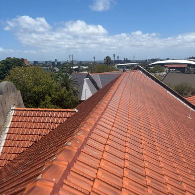 View of orange tiled rooftops under a bright blue sky.