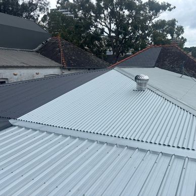 Various rooftops with metal and tiled materials under a cloudy sky.