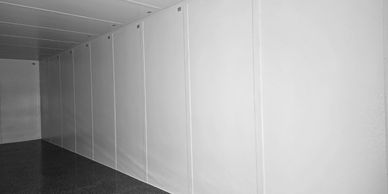 Empty white panels line a corridor with a dark floor.