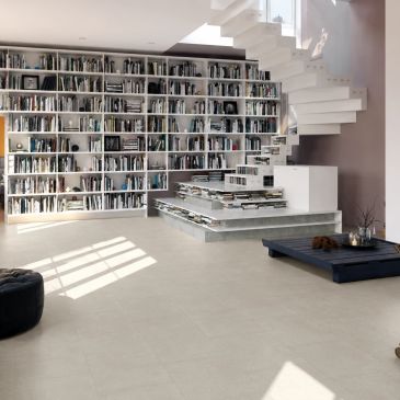 Modern living room with a large bookshelf and a floating staircase.