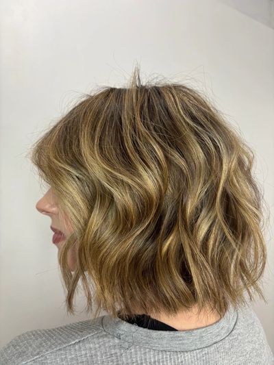 Wavy bob haircut with blonde highlights.