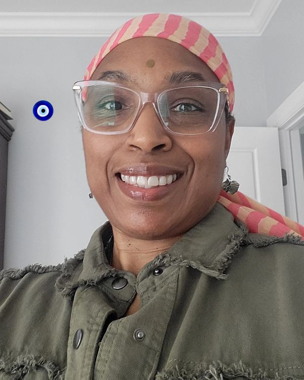 Smiling person wearing glasses and a striped headscarf.