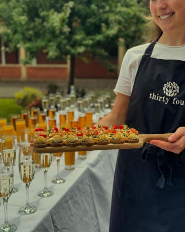 Waiter holding a platter of appetizers at an outdoor event.