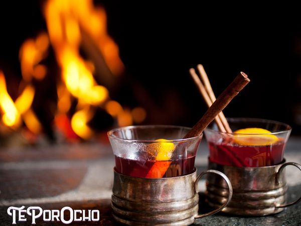 Tazas de té especiado de naranja y canela con fuego reconfortante al fondo