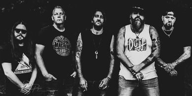 Black and white photo of a five-member rock band with tattoos and casual attire.