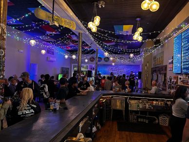 Crowded bar with festive lights and patrons enjoying their time.