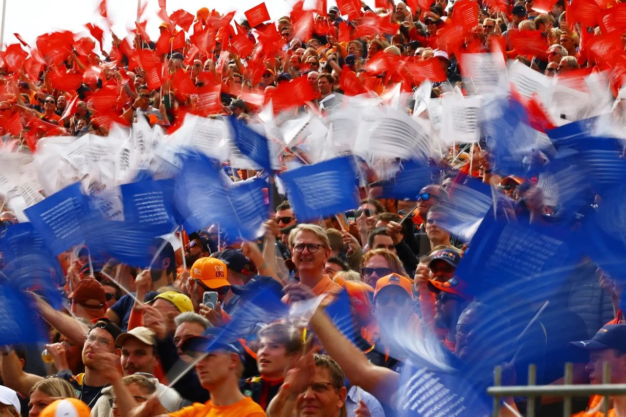 “Dutch F1 fans waving red, white, and blue flags at Circuit Zandvoort during the Formula 1 Dutch Grand Prix.”