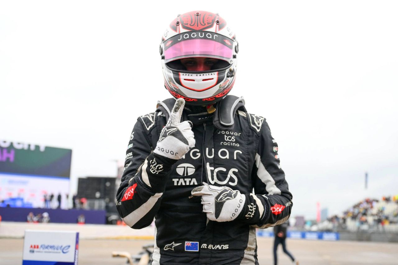 Mitch Evans in Jaguar TCS Racing overalls celebrates Berlin E-Prix win at Tempelhof, pointing to camera in helmet and gloves.