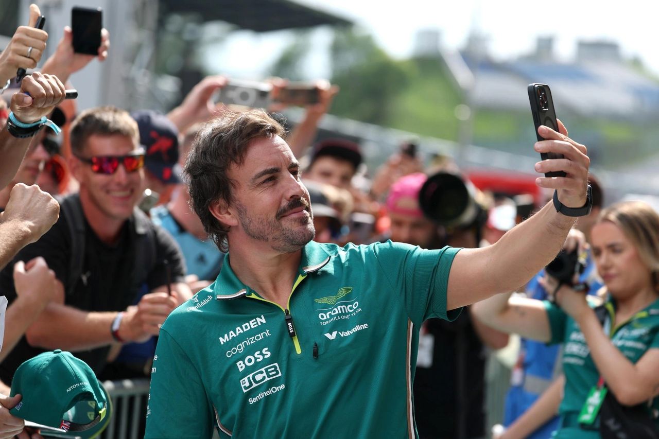 Fernando Alonso wearing Aston Martin team kit takes a selfie with fans in the paddock at the 2025 Austrian Grand Prix. Fernando Alonso wearing Aston Martin team kit takes a selfie with fans in the paddock at the 2025 Austrian Grand Prix.