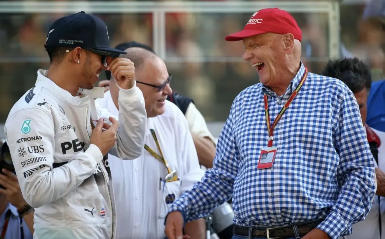Lewis Hamilton smiling with Niki Lauda in the Formula 1 paddock, a tribute to their close relationship that shaped Hamilton’s Mercedes career.
