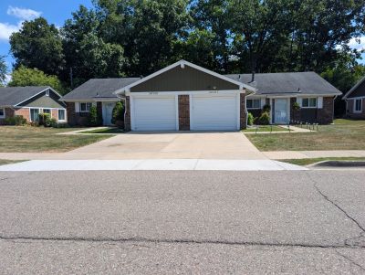 Two attached houses with garages in a suburban neighborhood.