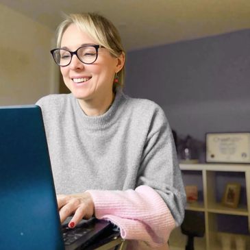Smiling woman working on a laptop in a cozy room.