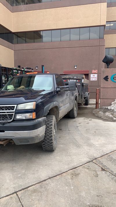 Truck with dump trailer loading up junk for haul away