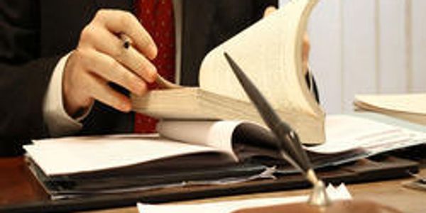 A person in a suit flipping through a book at a desk.