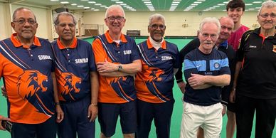 A team of bowls club members standing on an indoor bowls green