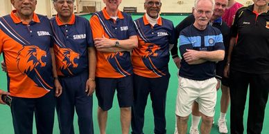 A team of bowlers standing on an indoor bowls green