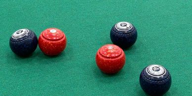 Colourful bowls and a mat on an indoor bowls club green