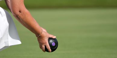 Close up of a person's bowling arm holding a bowl at a bowling club