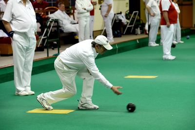 A man bowling on Century Bowls Club indoor green