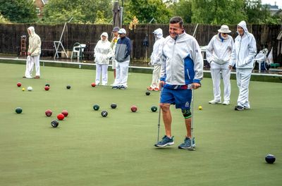 A bowls club member with walking sticks playing on Century Bowls Club outdoor bowls green
