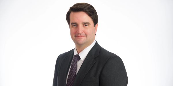 Portrait of a man in a suit with a neutral expression.