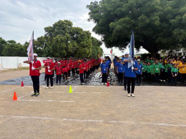 Groups of students in colored uniforms lined up for an outdoor event.