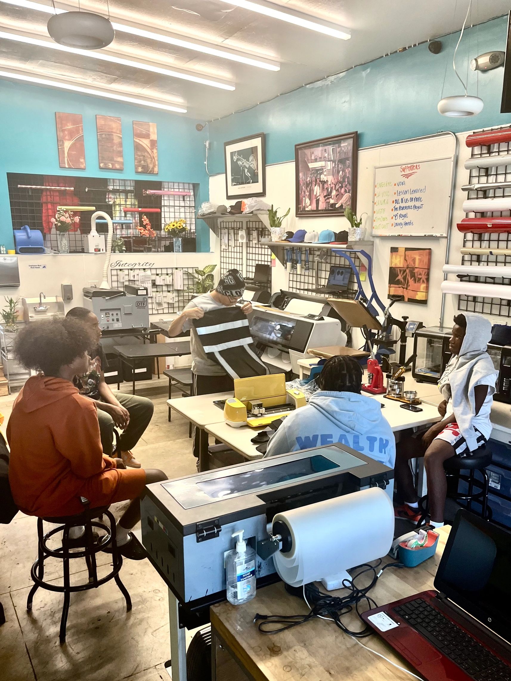 A group of young people in a vibrant workshop with printing equipment and materials.