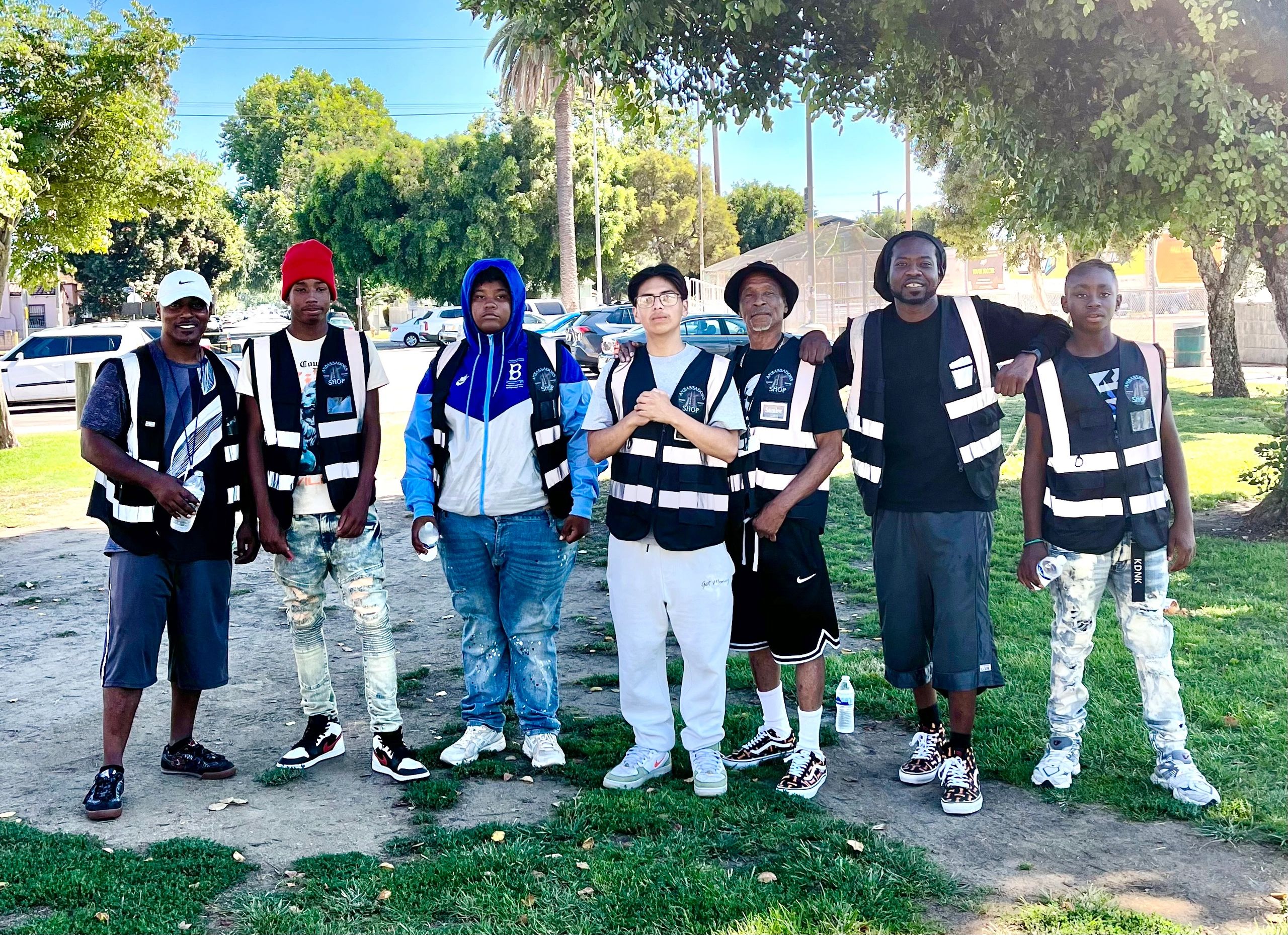 Group of seven men wearing reflective safety vests outdoors.