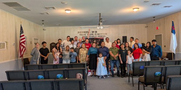 Group photo in a church hall with diverse members and children.