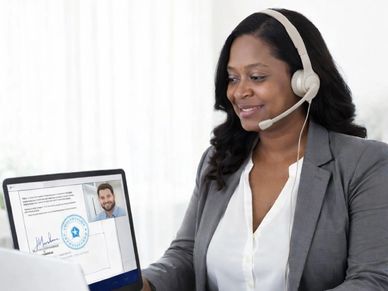 A woman talking on a laptop in a meeting with headphones on