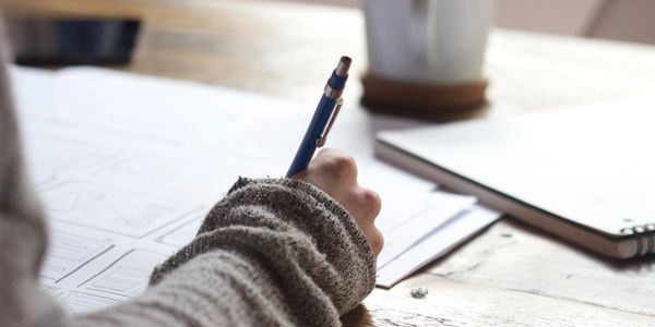 Woman writing with notebooks and cup of coffee.