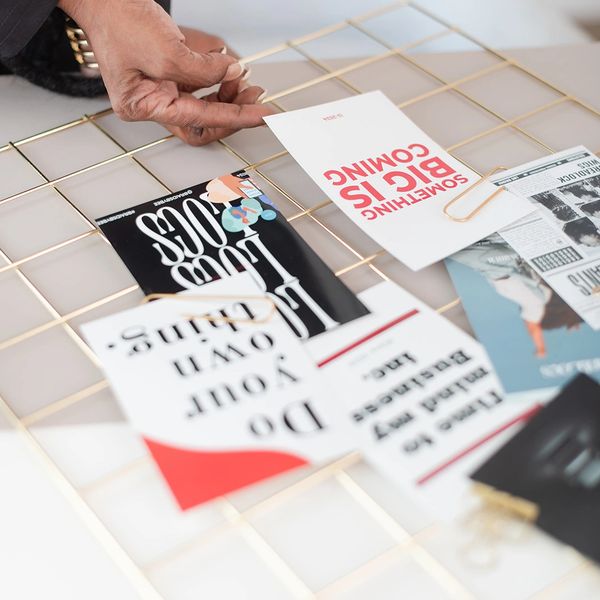 A person arranging motivational cards on a gold grid display.
