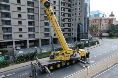 A large yellow crane truck parked on a city street.