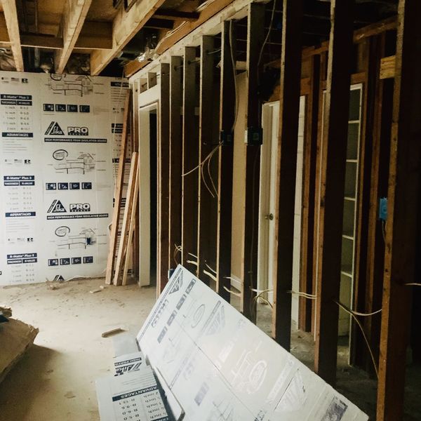 Interior of a building under construction with exposed wooden framing and insulation boards.