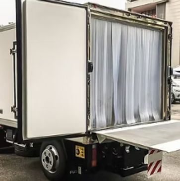 White delivery truck with open rear doors and lift gate in urban area.