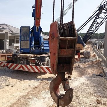 A crane with a large hook at a residential construction site.