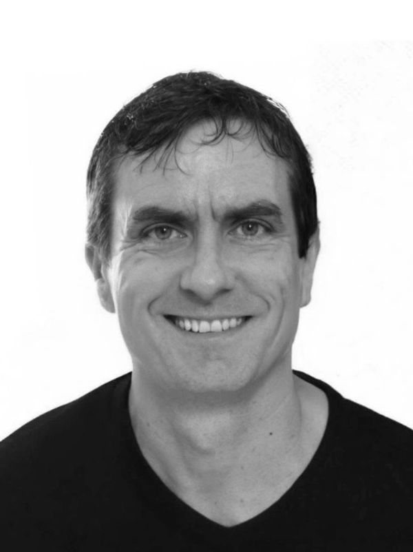 Smiling man with dark hair in a black shirt.