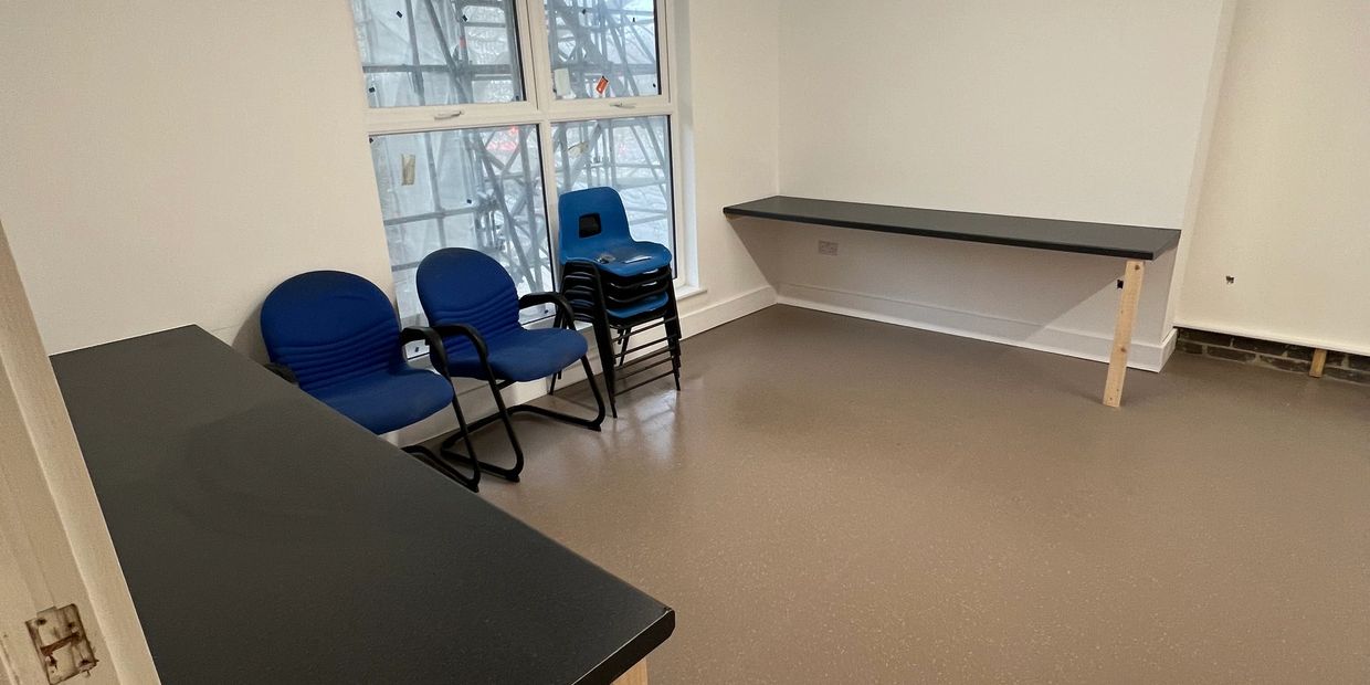 Empty office room with blue chairs and black desks.