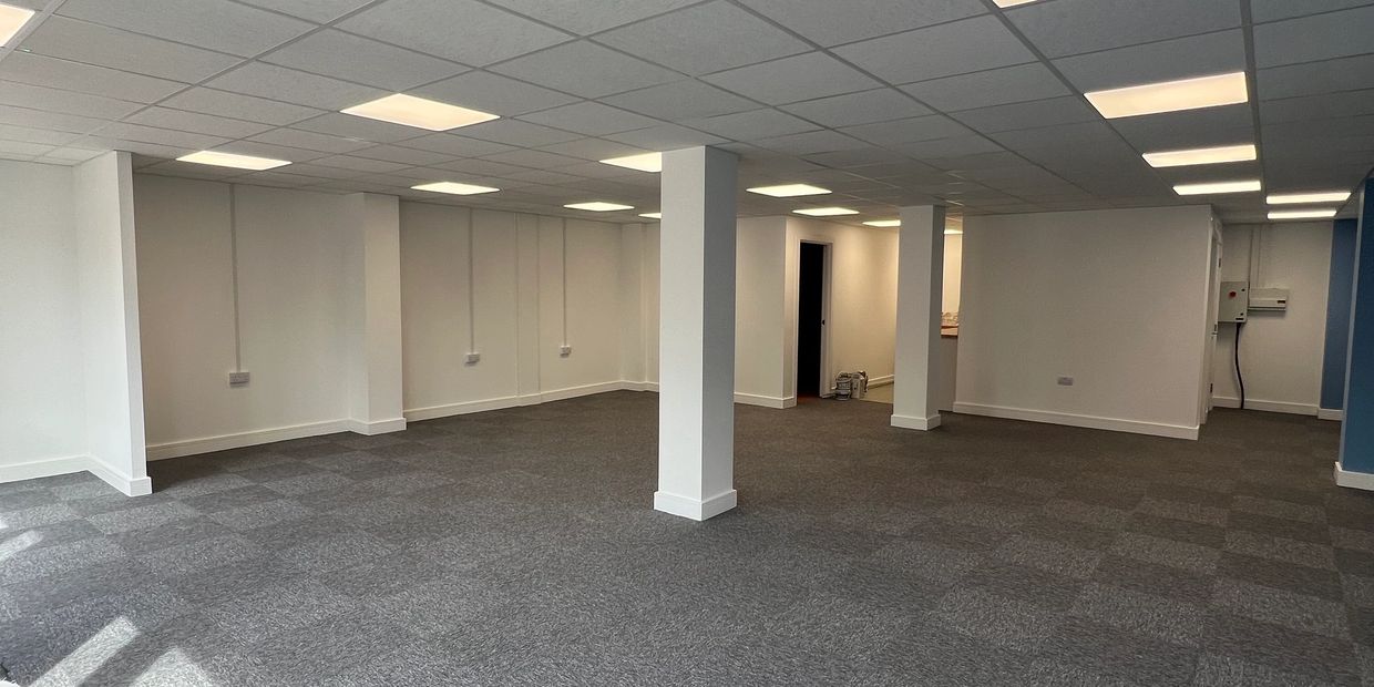 Empty office space with carpet and columns.
