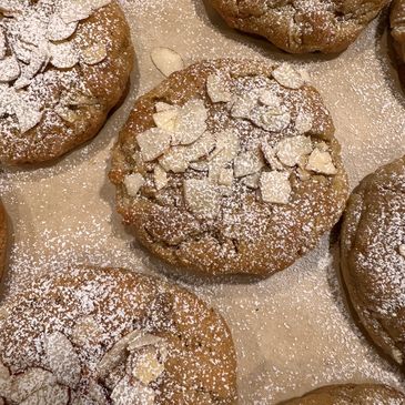 Freshly baked cookies topped with almond slices and powdered sugar.